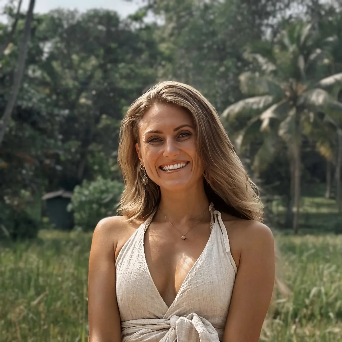 Alina Matzek lacht unbeschwert in der Natur, im Hintergrund Palmen